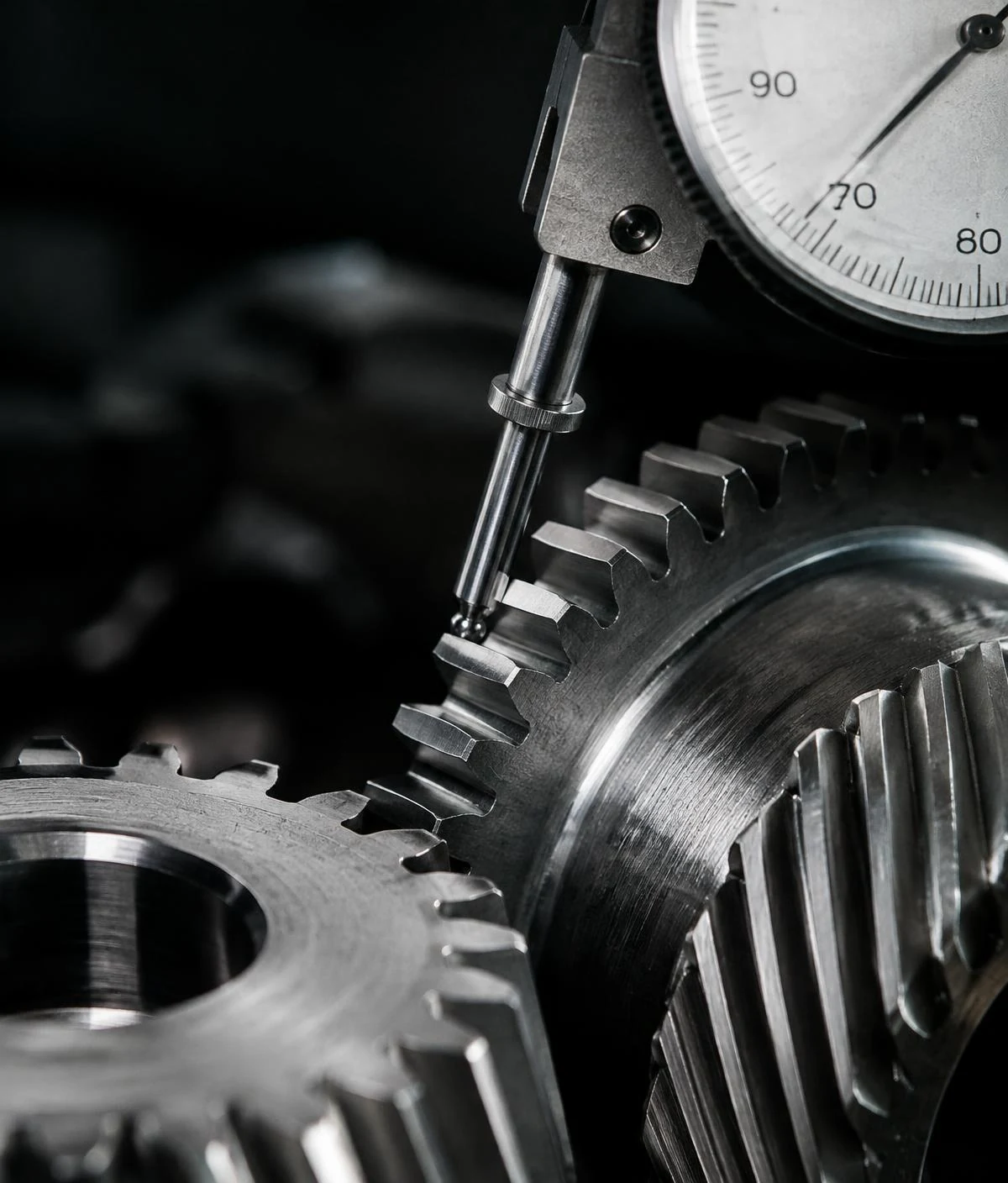Close-up of a precision dial gauge measuring machined steel gear teeth